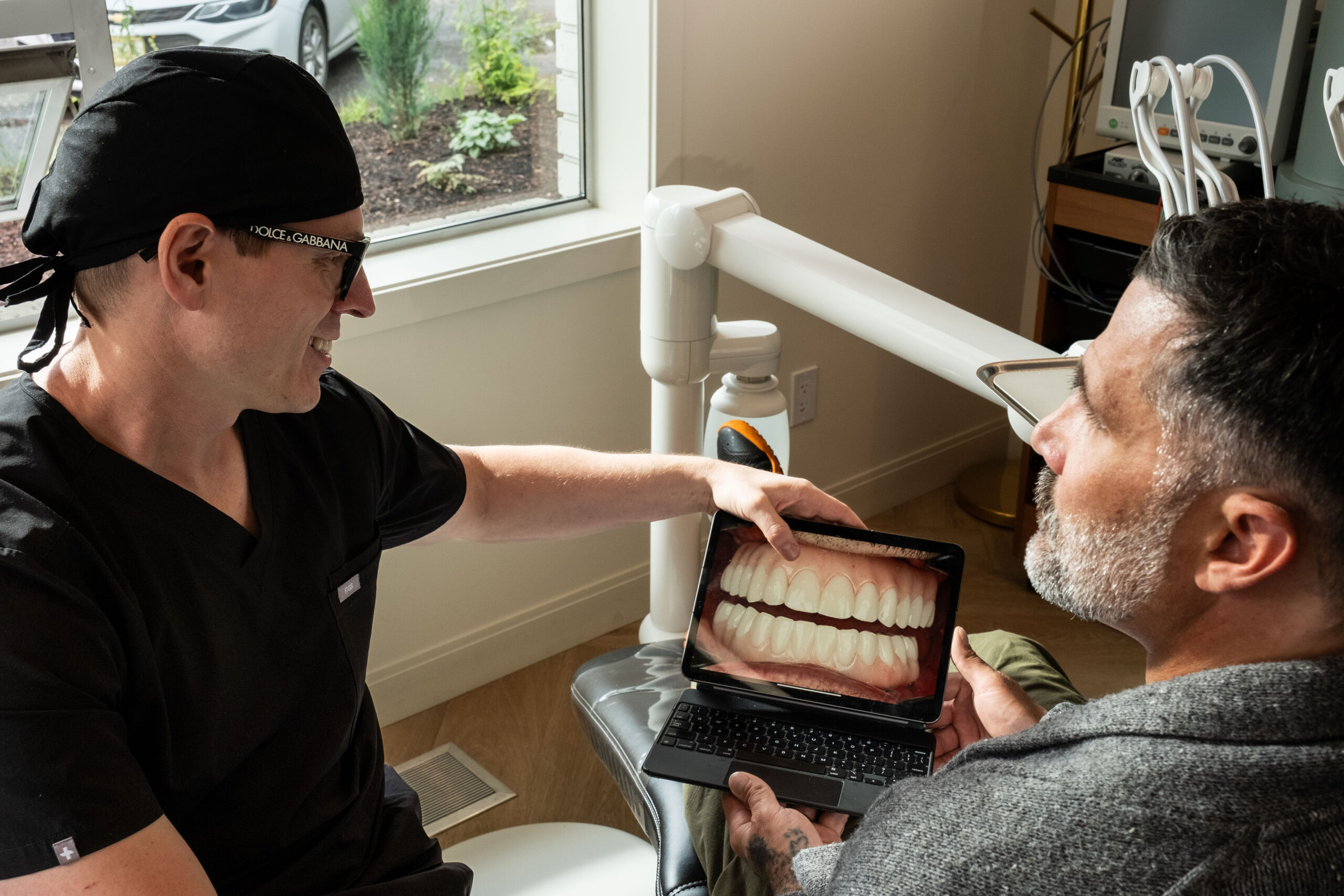 'http://A%20dentist%20shows%20a%20patient%20a%20digital%20image%20of%20teeth%20on%20a%20tablet%20during%20a%20dental%20consultation%20in%20a%20modern%20office,%20with%20dental%20equipment%20and%20a%20window%20in%20the%20background.