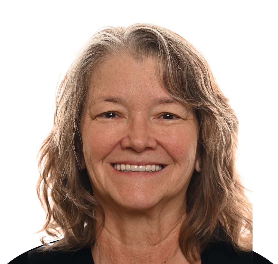 'http://A%20middle-aged%20woman%20with%20wavy,%20shoulder-length%20gray%20hair%20smiles%20warmly%20at%20the%20camera%20against%20a%20plain%20white%20background.%20She%20is%20wearing%20a%20black%20top.